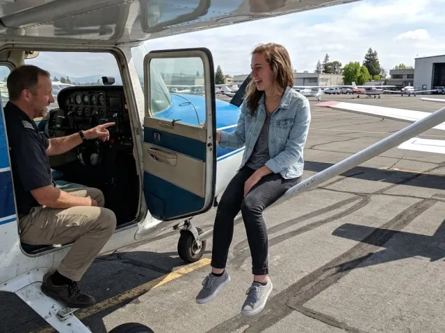 An instructor briefing a young student in the cockpit